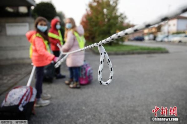 当地时间10月20日,在意大利北部贝卢斯科,孩子们拿着绳子保持社交距离,在志愿者的护送下走向学校。图为绳子上每隔一定距离就打一个结,帮助孩童确定距离。 点击进入下一页
